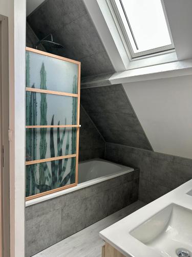 a bathroom with a bath tub and a sink at Villa l'Escale in Daubeuf-Serville