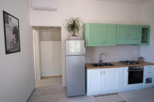 a kitchen with green cabinets and a white refrigerator at Pioppi Apartments in Pioppi