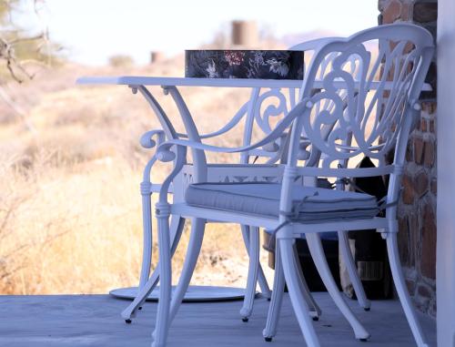 a white chair and a table on a porch at Tsauchab River Camp in Sesriem