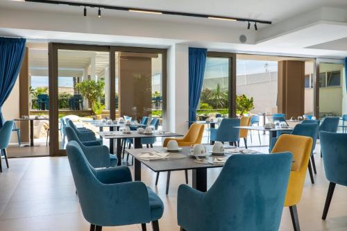 a restaurant with tables and chairs and windows at Resort La Battigia Beach & Spa in Alcamo Marina