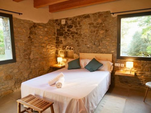 a bedroom with a bed in a stone wall at Mas Ca la Rossa in Girona