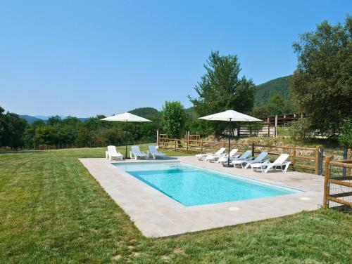 a swimming pool with lounge chairs and umbrellas at Mas Ca la Rossa in Girona