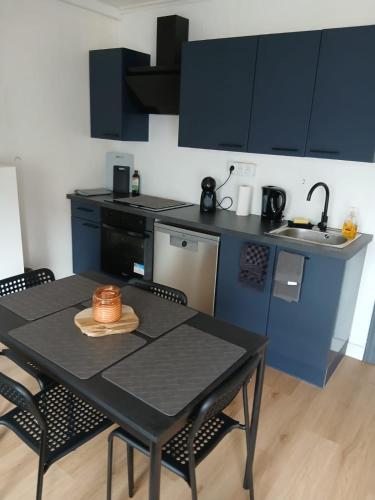 a kitchen with a black table with chairs and a sink at Maison Jardin aéroport Charleroi in Charleroi