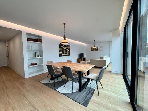 a dining room and living room with a wooden table and chairs at Green Coast Apartments in Capelas