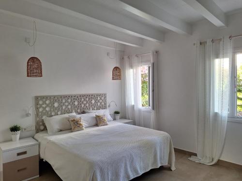 Un dormitorio blanco con una cama grande y dos ventanas. en B5 Villa Sueños, en Santo Tomás