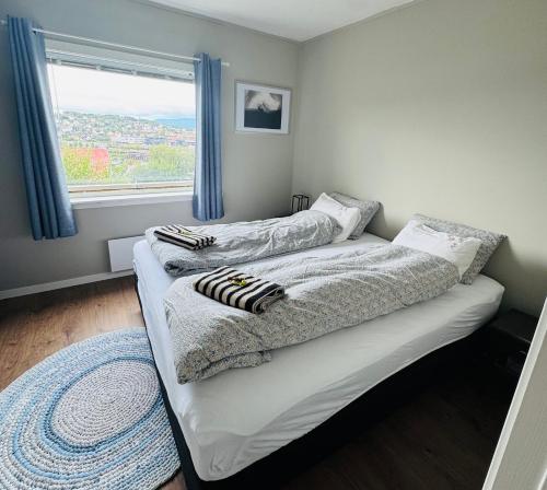 two beds in a room with a window at Tøttatoppen leilighet in Narvik