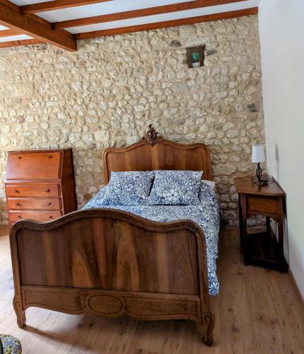 a bedroom with a wooden bed and a stone wall at Gîte Belle, Piscine privée, vue sur la campagne in Nonac
