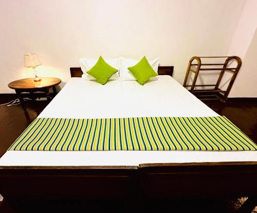 a large bed with green and yellow pillows on it at Rosewood Bungalow in Bandarawela