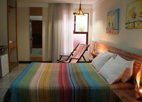 a bedroom with a bed and a chair in it at Pousada Manga Rosa Beira Mar in Natal