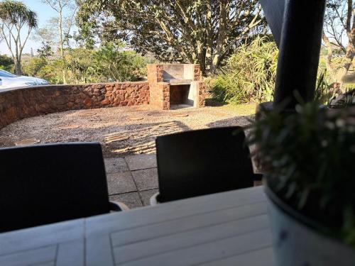 a table with two chairs and a stone wall at Casa Madeira 1 in Gillitts