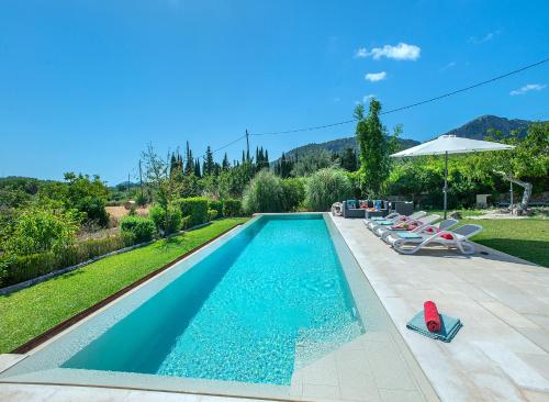 une piscine avec des chaises et un parasol dans l'établissement Owl Booking Villa La Rafal - Luxury Retreat with Mountain Views, à El Port