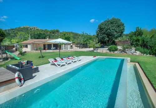 una piscina con tumbonas y sombrilla en Owl Booking Villa La Rafal - Luxury Retreat with Mountain Views, en Port de Pollença (Puerto Pollensa)