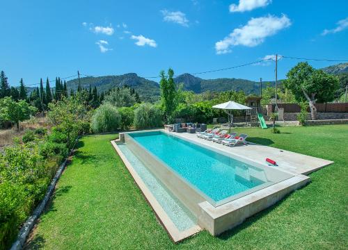 una piscina en un patio con sillas y sombrilla en Owl Booking Villa La Rafal - Luxury Retreat with Mountain Views, en Port de Pollença (Puerto Pollensa)