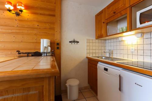 eine kleine Küche mit Holzschränken und einer Spüle in der Unterkunft travelski home classic - Résidence Meijotel in Les Deux Alpes