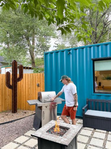 a man cooking food on a grill in a backyard at Cargo Casita Shipping Container Tiny Home in Colorado Springs