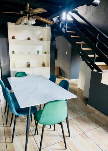 a dining room with a white table and blue chairs at 13 Orion Aparment in Polokwane