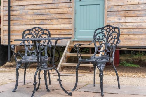 two black chairs and a table in front of a house at Hot Tub Luxury Glamping - Private Stargazing Patio in Yarpole