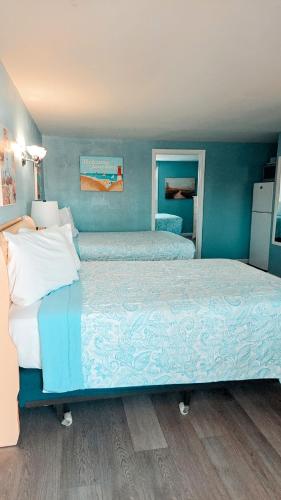a bedroom with two beds with blue walls at Pelican Point Motel in Point Pleasant Beach