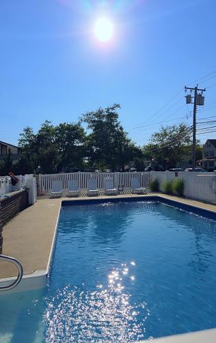 a swimming pool with a white picket fence at Pelican Point Motel in Point Pleasant Beach