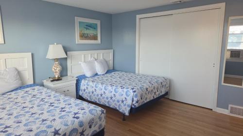 a bedroom with two beds with blue walls and a window at Pelican Point Motel in Point Pleasant Beach