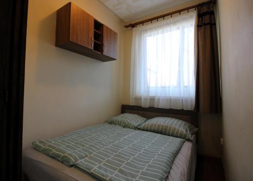 a bed in a small room with a window at Áron Apartment in Nyíregyháza