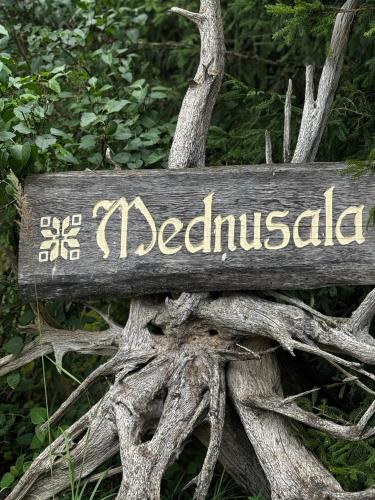 a sign on a tree with the name of a woodland at Holiday house Medņusala in Mālpils