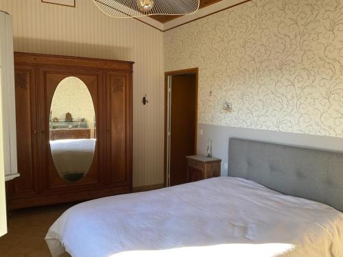a bedroom with a large bed and a mirror at Maison paisible Noël et Rosalie 