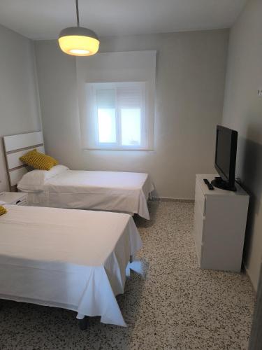 a room with two beds and a tv on a dresser at Casacasini 1B in Málaga