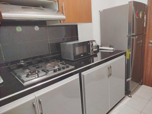 a kitchen with a stove and a microwave at app entre aéroport M5 et nearshore sidi maarouf in Bouskoura