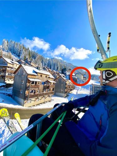 a person riding a ski lift with a red circle at Byt na svahu Sonnenalpe Nassfeld in Hermagor