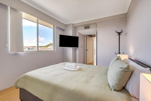 a bedroom with a large bed and a flat screen tv at 73R Abnb-Style Apartment-Quiet, Pool&Gym, Parking & 10mins drive to Centennial in Sydney