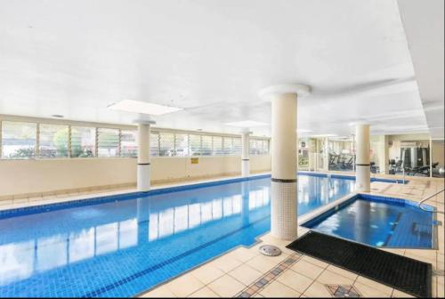 a large swimming pool in a building at 73R Abnb-Style Apartment-Quiet, Pool&Gym, Parking & 10mins drive to Centennial in Sydney