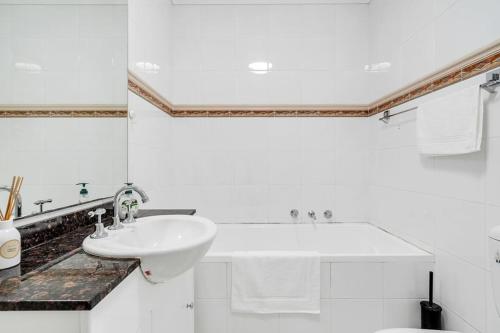 a white bathroom with a sink and a toilet at 73R Abnb-Style Apartment-Quiet, Pool&Gym, Parking & 10mins drive to Centennial in Sydney