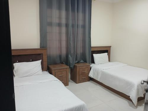 a bedroom with two beds with white sheets at زهرة الوادي 1 للشقق المفروشة in Salalah