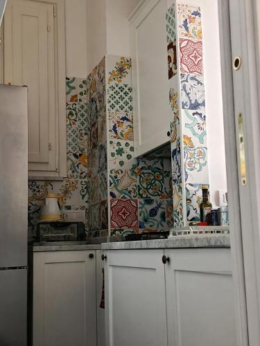 a kitchen with white cabinets and colorful tiles on the wall at Salerno Eremita Apartment in Salerno