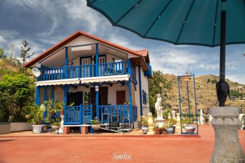 a blue house with a blue balcony and an umbrella at Chalet, breathtaking sea view with large jacuzzi in Almuñécar