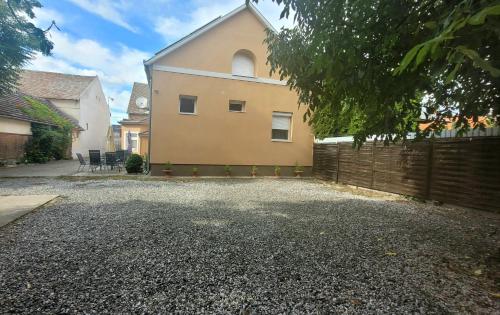 a house with a fence and a gravel driveway at Megyeház Apartman in Makó