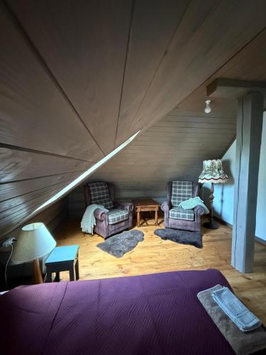 a room with two chairs and a bed in a attic at Holiday house Medņusala in Mālpils