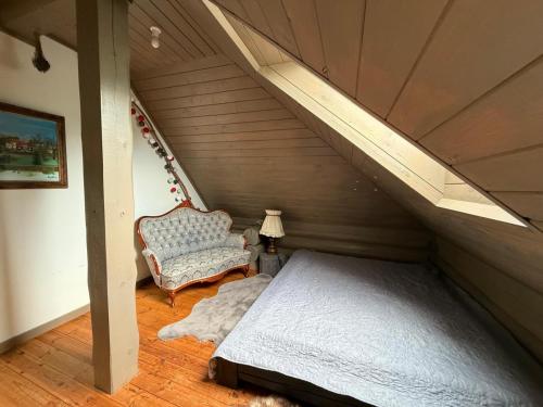 a attic room with a bed and a chair at Holiday house Medņusala in Mālpils