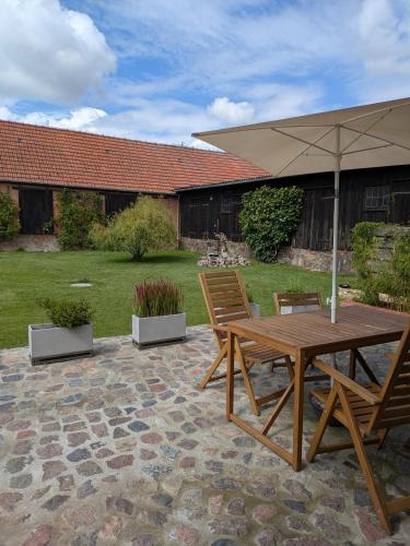 a wooden table and chairs with an umbrella on a patio at Ferienwohnung im Kontor Penzlin in Penzlin