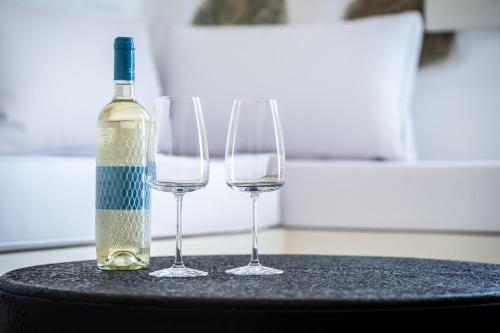 a bottle of wine and two wine glasses on a table at CALDERA CASABLANCA in Ano Meria