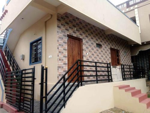 a house with a staircase and a wooden door at Shiva Homestay Hampi in New Hampi