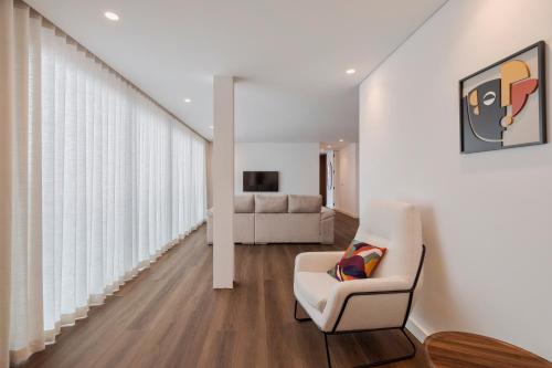 a living room with a white chair and a couch at Penthouse 9 in Setúbal