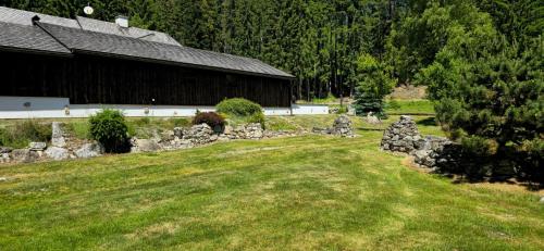 a barn with a stone wall in front of a yard at Hájovna u Jindřicha in Nová Pec