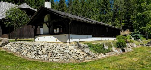 a building with a stone wall in front of it at Hájovna u Jindřicha in Nová Pec