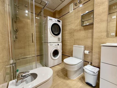 a bathroom with a toilet and a washing machine at Reinapart Patacona Beachfront Seaview in Valencia
