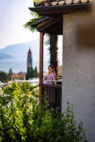 a woman standing on a balcony talking on a cell phone at Suite Stays by Hotel La Perla in Ascona