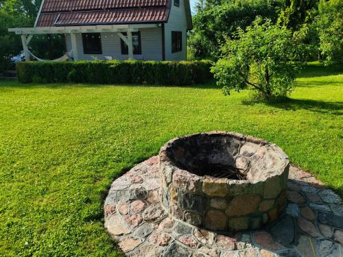 a stone fire pit in a yard with a house at Domek na Kaszubach w Pomysku Małym in Soszyca