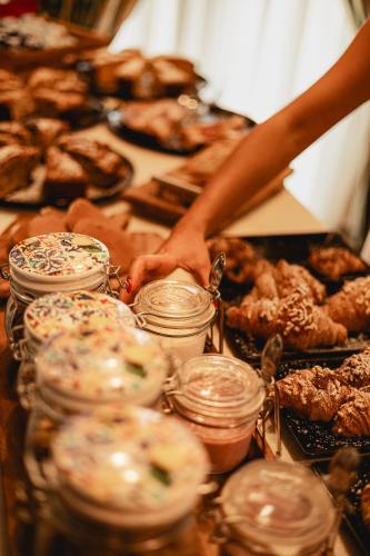 a person putting food in jars on a table with pastries at Hotel Petite Fleur in Roccaraso