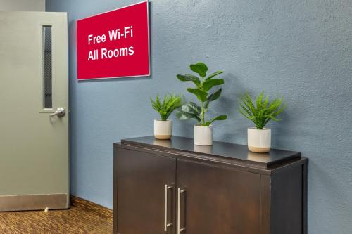 a cabinet with three potted plants on top of it at HomeTowne Studios & Suites by Red Roof Greensboro in Greensboro